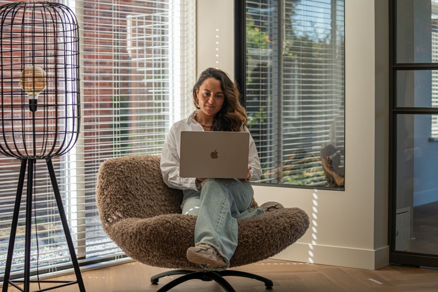 Romy werkt op een laptop in een fauteuil