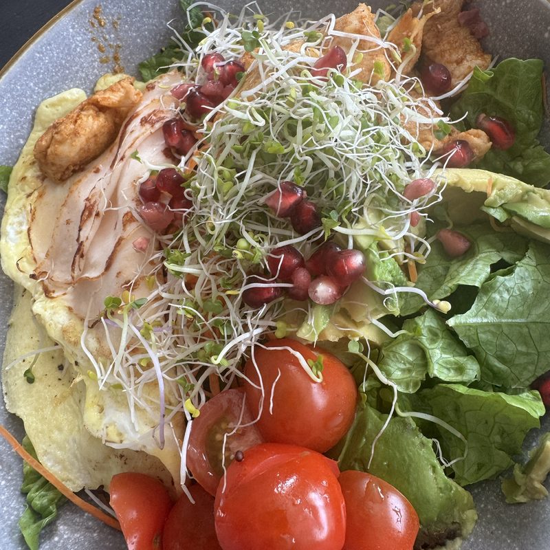 Bowl met kip, salade, cherrytomaten, granaatappel en kiemgroente
